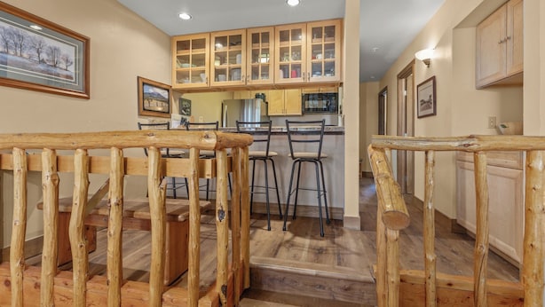 A wooden staircase leading to a kitchen with a dining area. - Short Walk to Slopes, Private W/D + Pool & Hot Tub (Steamboat Springs)