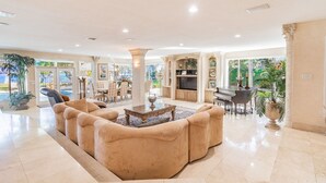 Uma sala de estar espaçosa com uma mesa de centro, sofás confortáveis, um piano e uma televisão.