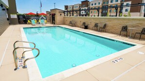 A swimming pool with a lifeguard chair, lounge chairs, and a patio area with tables and chairs. - Home2 Suites by Hilton Roseville Sacramento (Roseville)