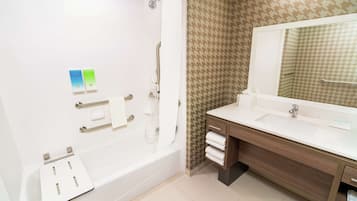 Une salle de bain moderne avec une baignoire, un grand miroir et un meuble-lavabo.