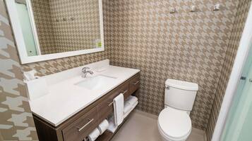 A bathroom with a white sink, mirror, and toilet.