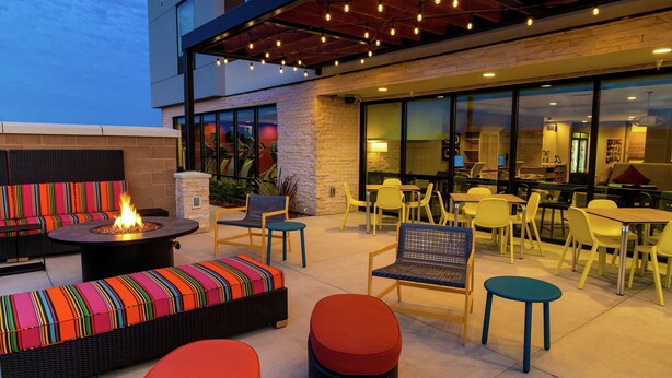 An outdoor seating area with a fire pit, colorful cushions, and yellow chairs. - Home2 Suites by Hilton Roseville Sacramento (Roseville)