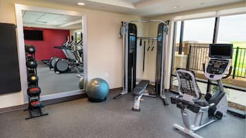 A gym with exercise equipment, a mirrored wall, and a view of the outdoors.