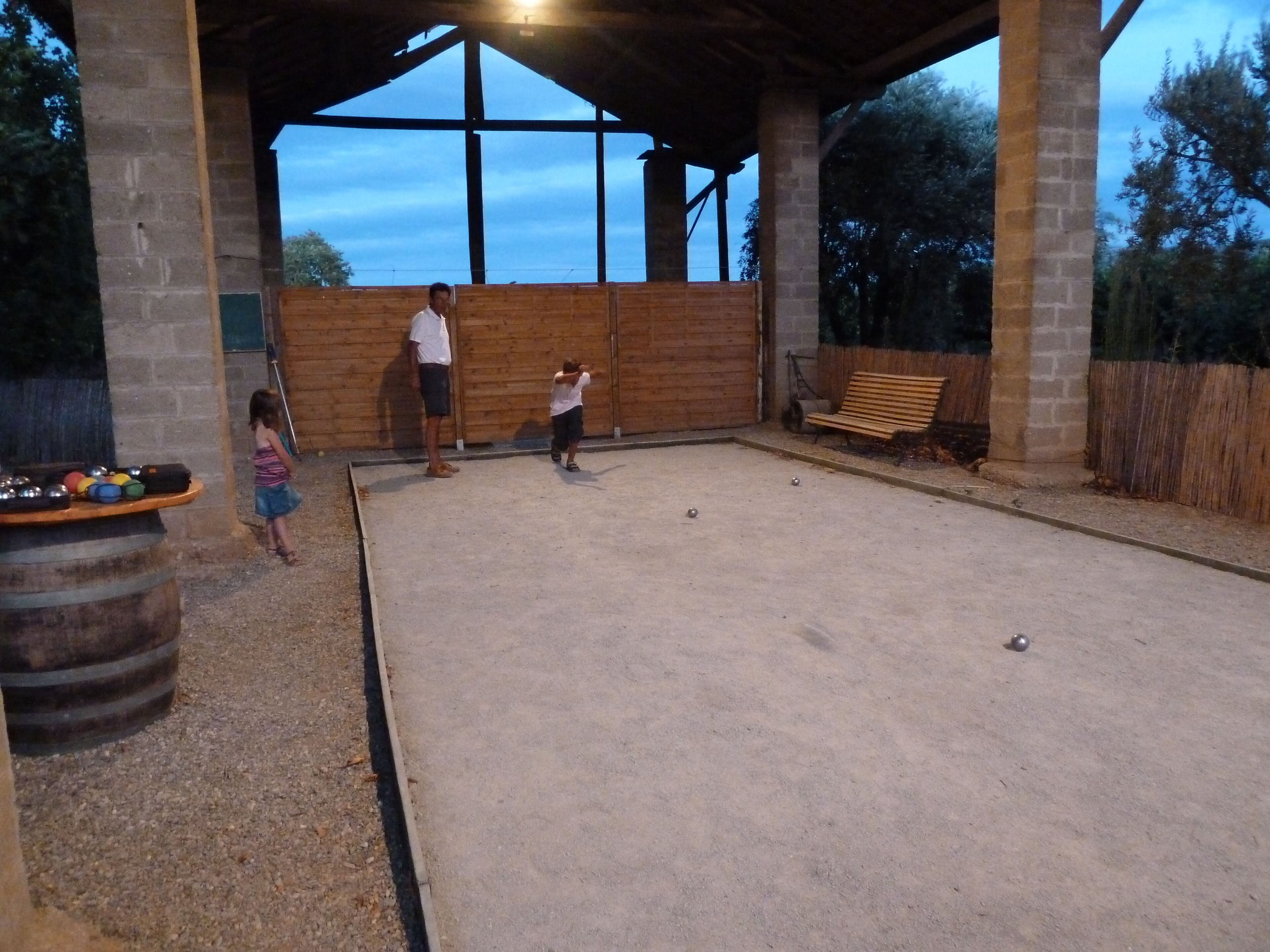 An outdoor billiards area with a wooden fence, a bench, and a table with balls.