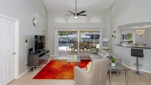 A modern living room with a glass coffee table, a beige sofa, and a red rug. - Gulf Access Waterfront, Pool with Heater, Friendly Neighborhood (Cape Coral)
