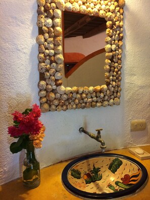 Un baño con lavamanos, espejo y decoración en la pared.