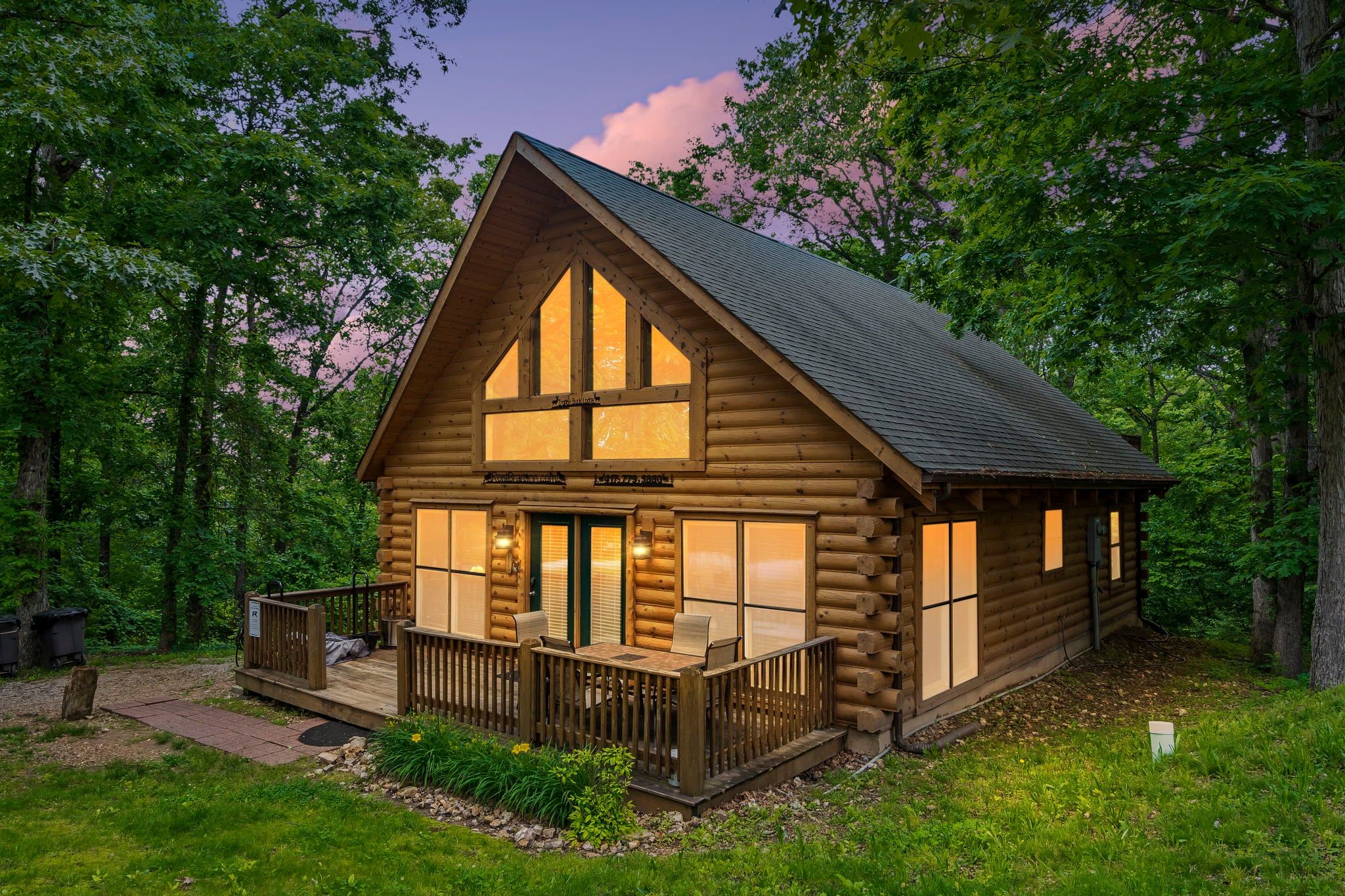 A log cabin with a porch, large windows, and a deck.