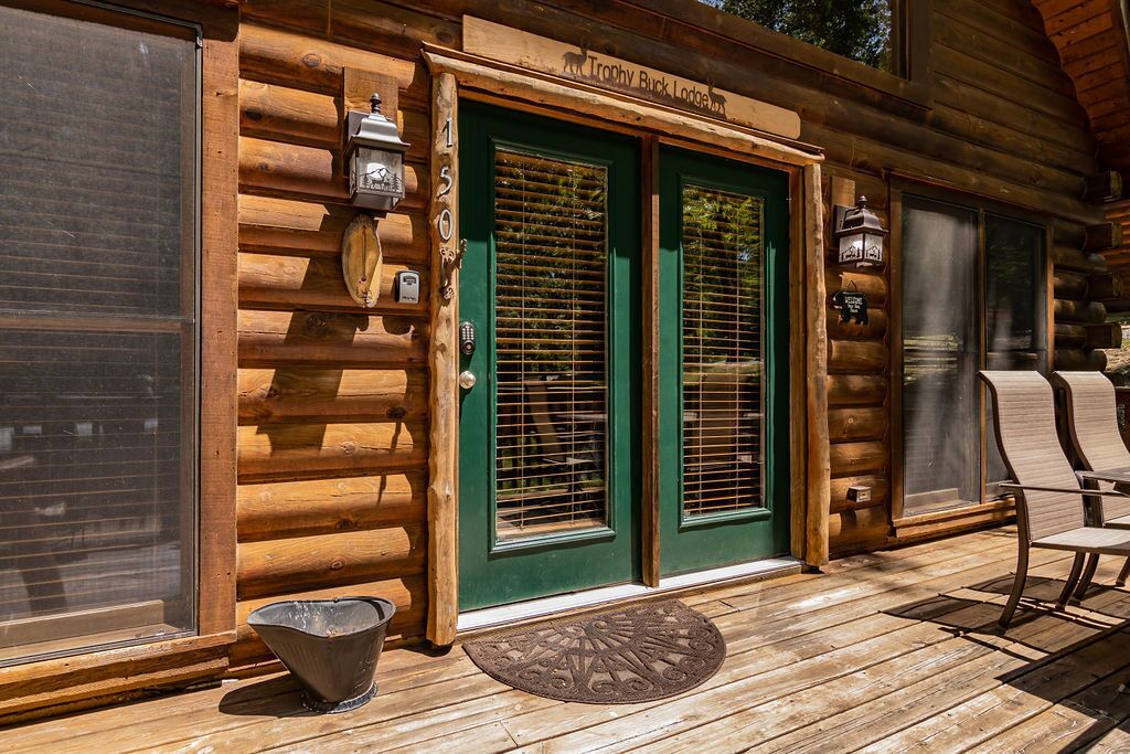 A wooden lodge with a green door, a wooden porch, and a sign reading "Trophy Buck Lodge."