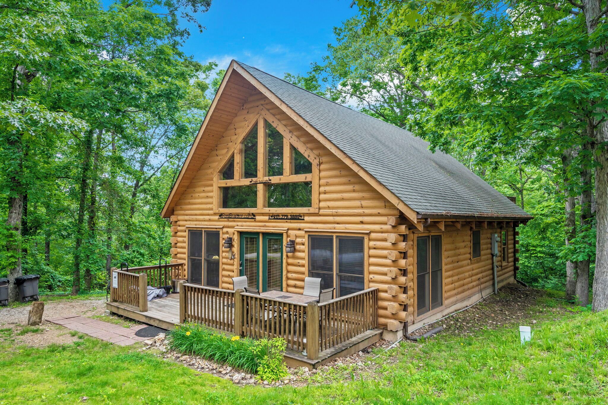 A log cabin with a porch, large windows, and a deck.