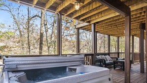 A hot tub under a wooden deck with a view of trees. - Upscale Log Cabin Over 2400 Sq Ft- Game Table-Free Tickets-Hot Tub-Car Charger-Near Thunder Ridge (Ridgedale)