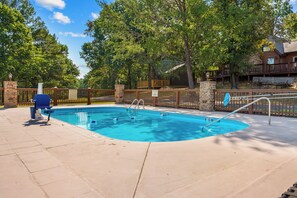 A rectangular swimming pool with a diving board, surrounded by a wooden fence, and a stone pillar. - Upscale Log Cabin Over 2400 Sq Ft Near Thunder Ridge w Hot Tub_Game Table_Free Tickets_Car Charger (Ridgedale)