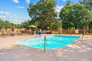 A swimming pool with a wooden deck, lounge chairs, and a wooden fence. - Upscale Log Cabin Over 2400 Sq Ft Near Thunder Ridge w Hot Tub_Game Table_Free Tickets_Car Charger (Ridgedale)