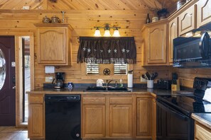 A wooden cabin kitchen with a dishwasher, stove, and various kitchen utensils. - Upscale Log Cabin Over 2400 Sq Ft- Game Table-Free Tickets-Hot Tub-Car Charger-Near Thunder Ridge (Ridgedale)