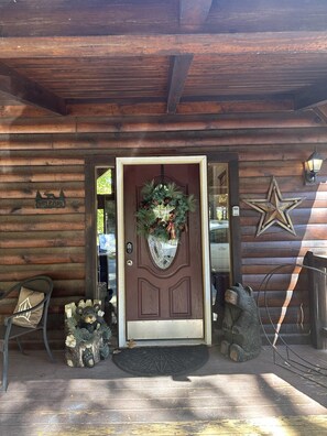 A wooden cabin entrance with a decorative wreath, a star decoration, and a bear sculpture on the porch. - Upscale Log Cabin Over 2400 Sq Ft- Game Table-Free Tickets-Hot Tub-Car Charger-Near Thunder Ridge (Ridgedale)