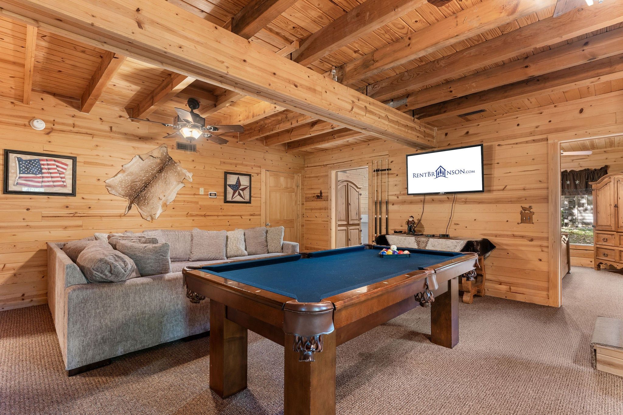A cozy room with a pool table, a sofa, and a television mounted on the wall.