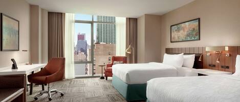 A hotel room with two beds, a desk, a chair, and a view of the city.