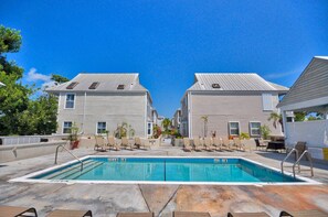 A swimming pool with lounge chairs and a small garden area in front of a building with a grey roof. - Key West Oasis on Duval Street : Private Hot Tub • Pool • Parking • 2 Balconies (Key West)
