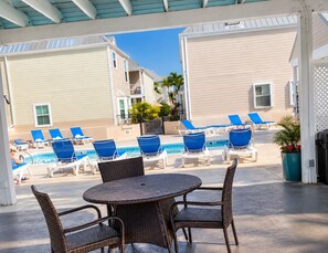 Un espace extérieur abrité comprenant une piscine, des chaises longues et une table.