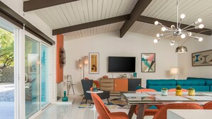 A modern living room with a TV, sofa, and dining area. - Alexander Sunrise - Luxury Midcentury Retreat (Palm Springs)