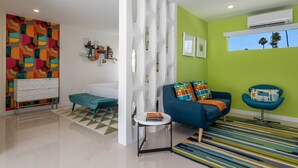 A modern living room with a sofa, a chair, a small table, and a colorful abstract wall art. - Alexander Sunrise - Luxury Midcentury Retreat (Palm Springs)