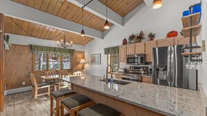 Une cuisine moderne dotée d’un grand îlot central, d’appareils électroménagers en acier inoxydable et d’éléments décoratifs en bois.