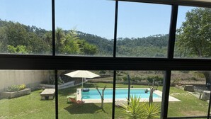 Une vue d’une piscine avec un espace patio, une pelouse et un mur en pierre.