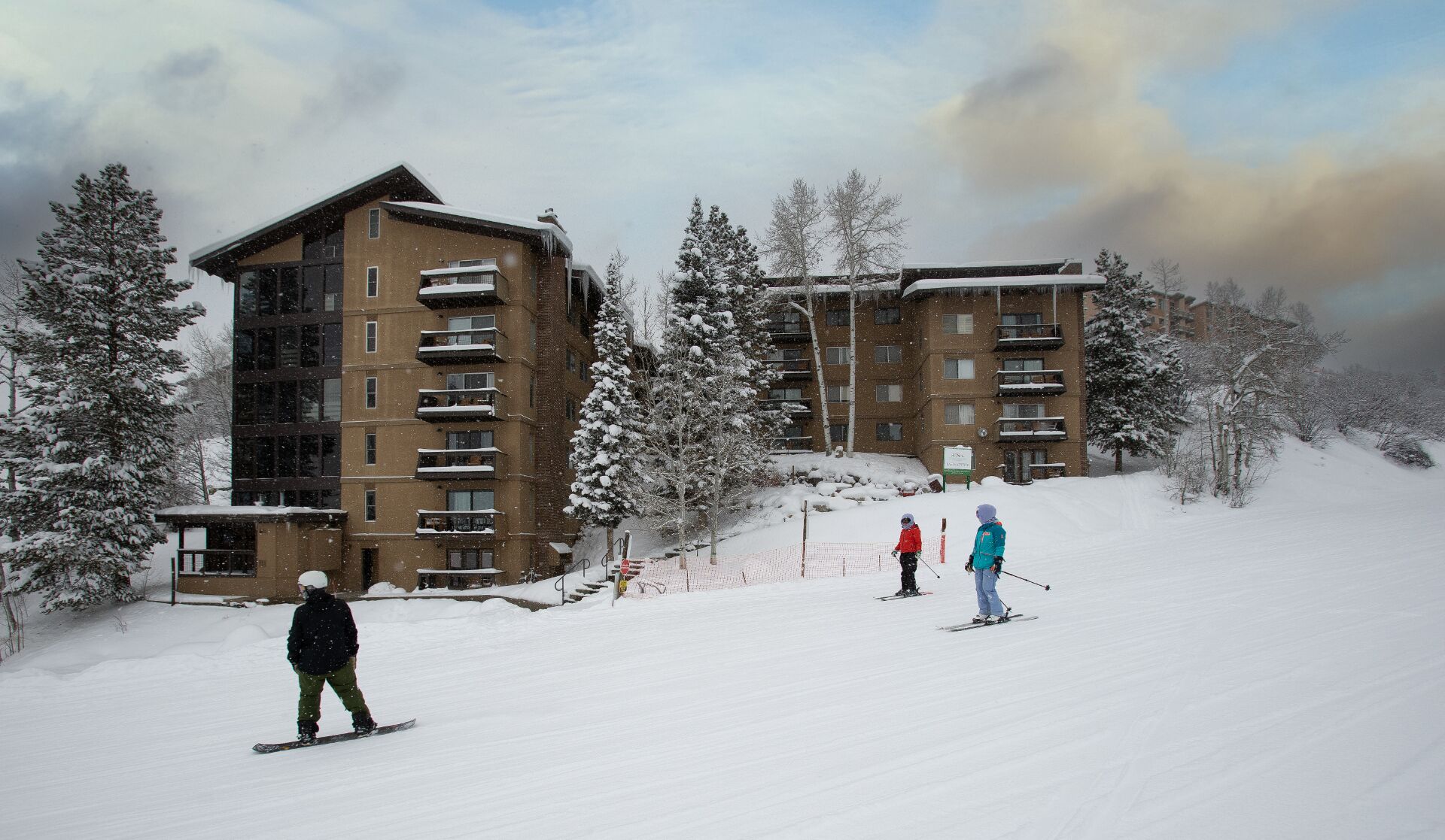 Ein mehrstöckiges Gebäude mit Balkonen, umgeben von schneebedeckten Bäumen.