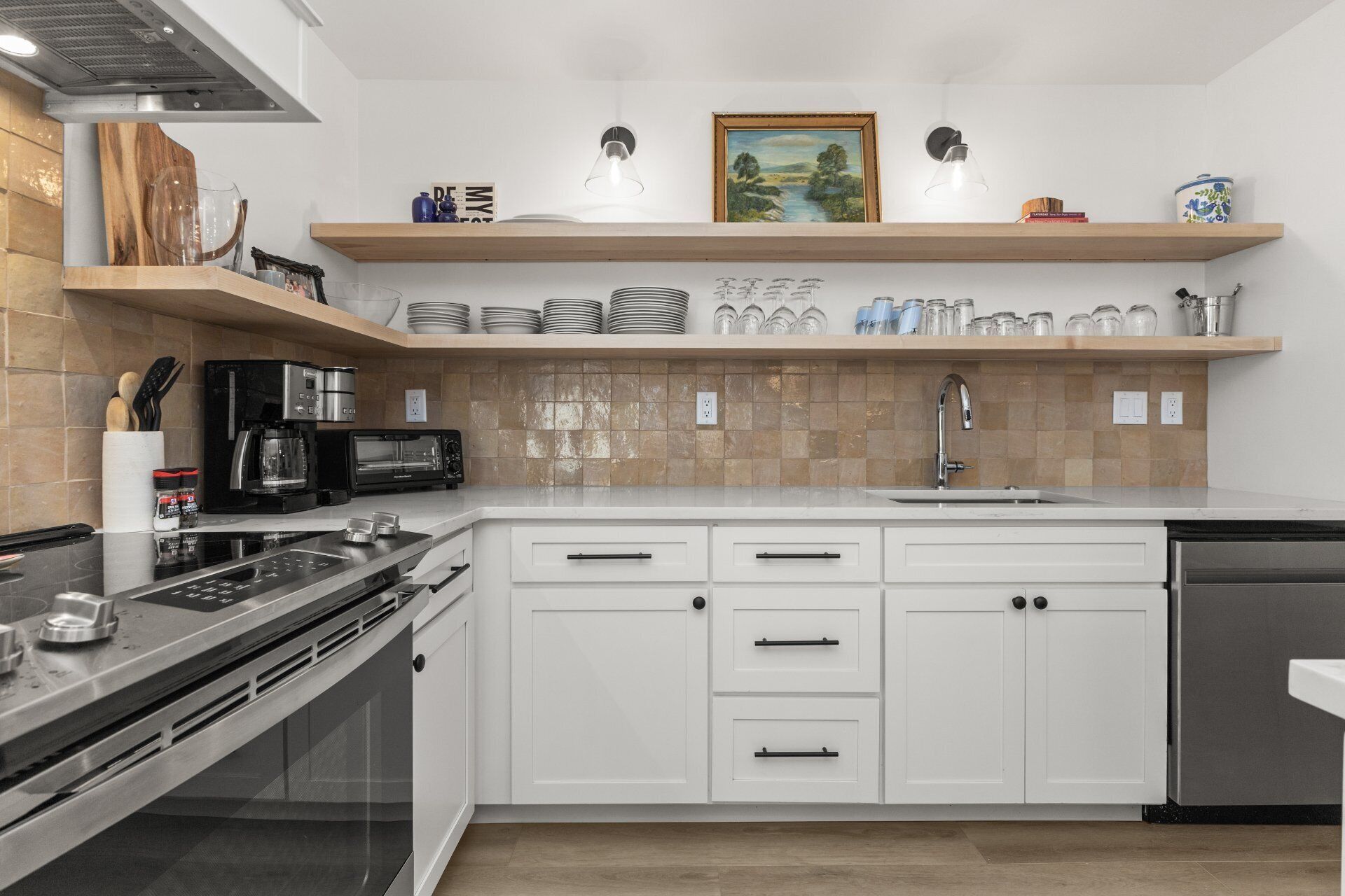 Una cocina moderna con armarios blancos, una estufa de acero inoxidable, un microondas y un lavavajillas.