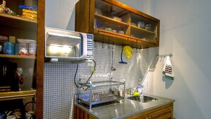 A kitchen with a microwave, sink, wooden cabinets, and a tiled backsplash.