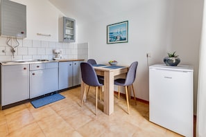 A kitchen with a dining table, chairs, a refrigerator, and a blue mat on the floor. - Apartments Katica, (15095), Zadar, hr (Zadar)