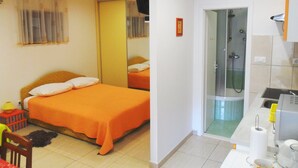 Une chambre d’hôtel comprenant un lit, un espace douche et une petite kitchenette.