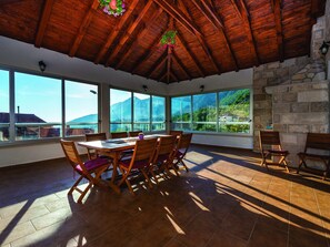 Enjoy expansive mountain views from the dining area with large windows and a stone wall.
