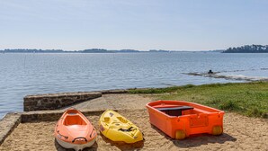 En sandstrand med tre kajaker och en liten båt.