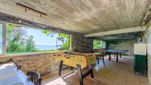 Ett fotbollsspelbord i ett rum med utsikt över havet, en stenmur och ett grönt bord.
