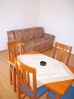Cozy room with a dining table for four, sofa, and ashtray.