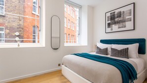 A modern bedroom with a bed, a window, and a city view. - 2 Bed 2 Bath Apartment Off Regent Street (London)