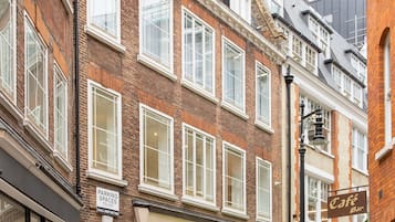 Une vue de rue d’un immeuble qui abrite un café et où l’on peut voir une enseigne indiquant la présence de places de stationnement.