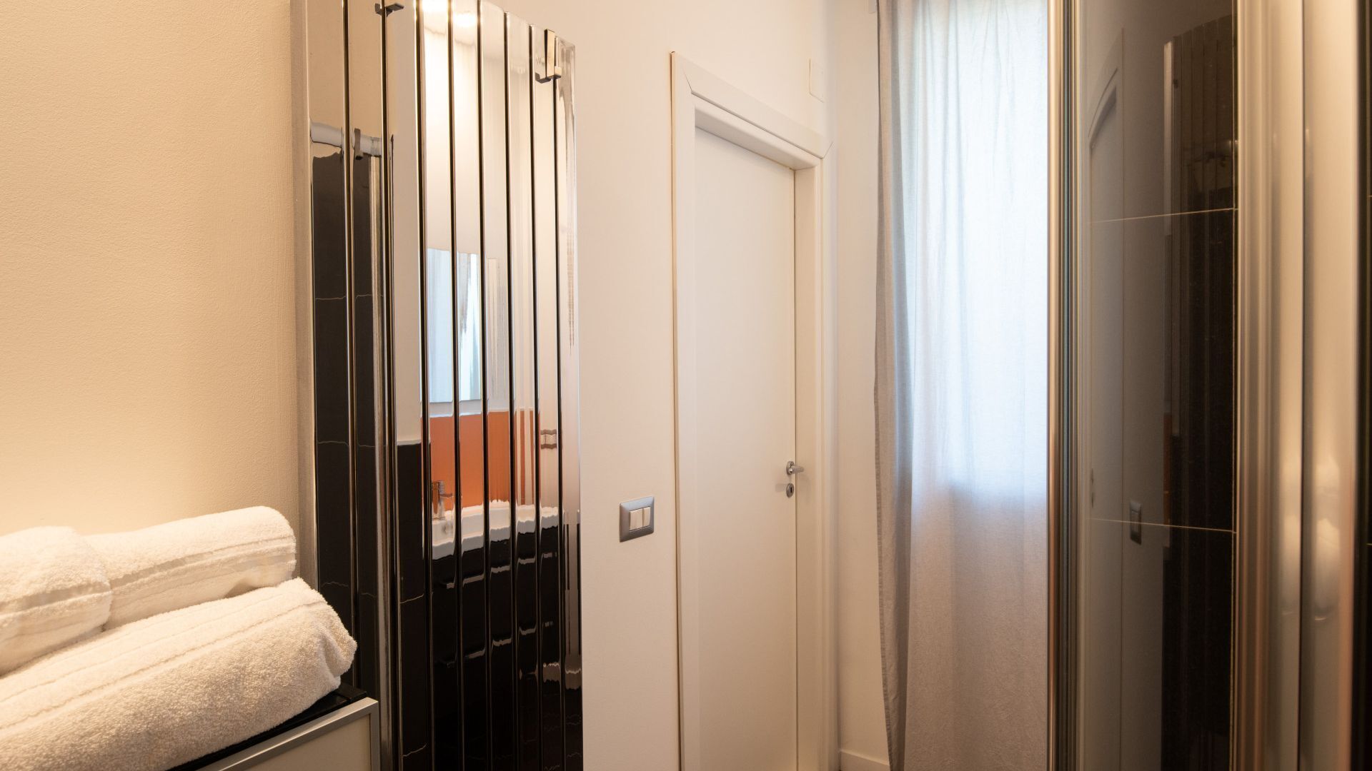 Un bagno con portasciuga asciugamani, zona doccia e una porta.