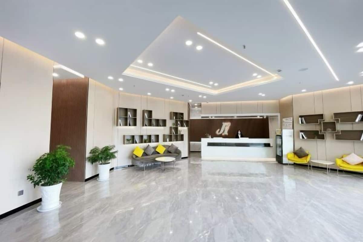 A modern reception area with a reception desk, seating, and potted plants.