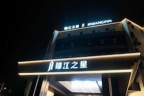 A hotel with illuminated signage, including a prominent name and a star symbol. - Jinjiang Inn (Taizhou Wanda Plaza Jiangzhou South Road) (Taizhou)