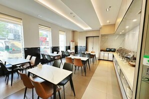 A restaurant with multiple tables and chairs, a counter with food display, and large windows. - Jinjiang Inn (Taizhou Wanda Plaza Jiangzhou South Road) (Taizhou)