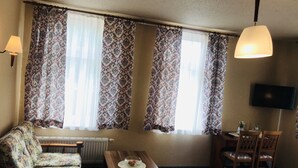Una habitación con sofá, mesa, silla, radiador y televisor montado en la pared.