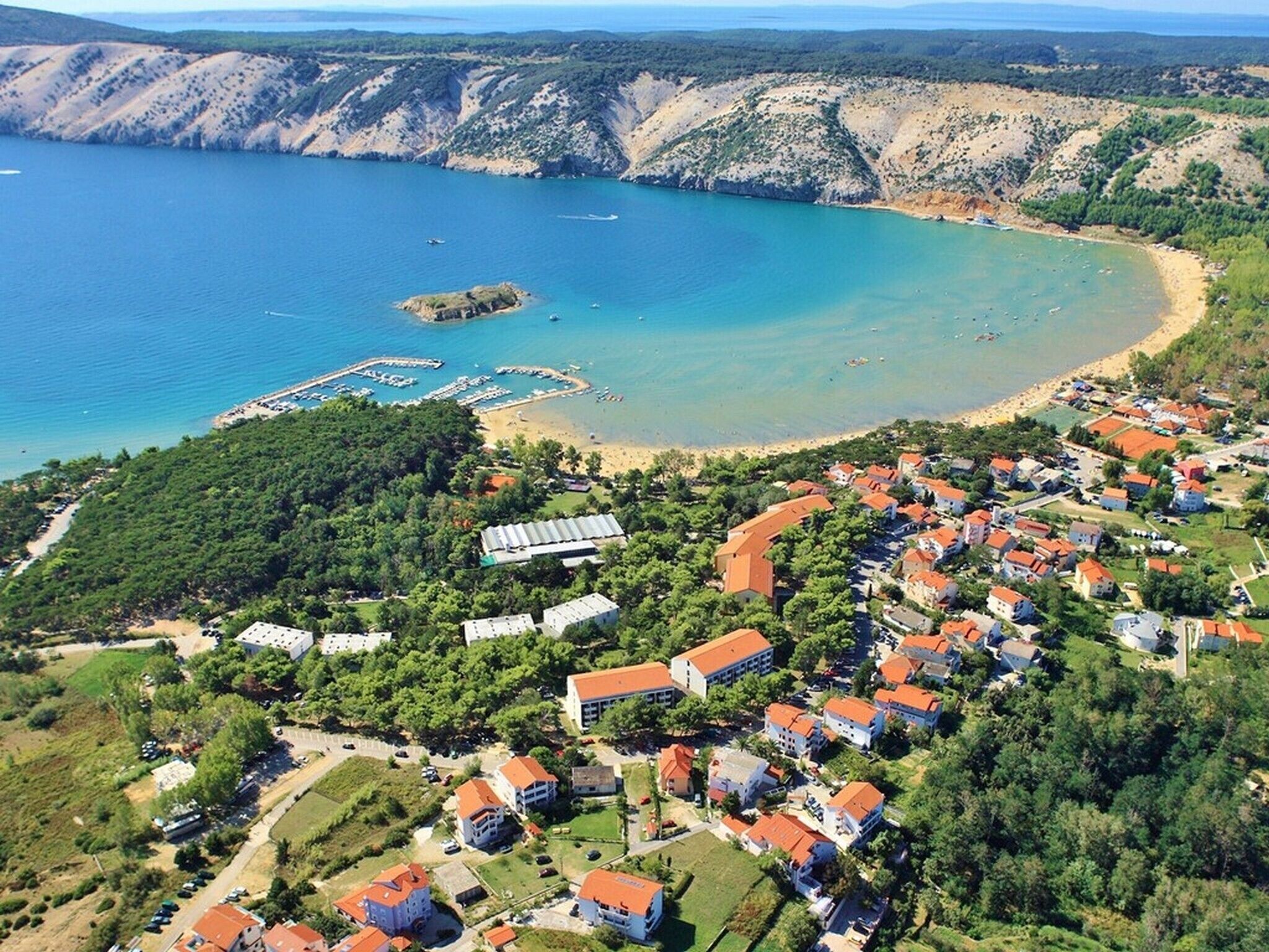 A coastal residential area with houses, a marina, and a beach.