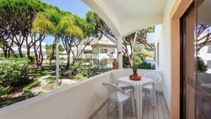 Un balcó amb taula i cadires, amb vista a un jardí ple d'arbres i plantes diverses.