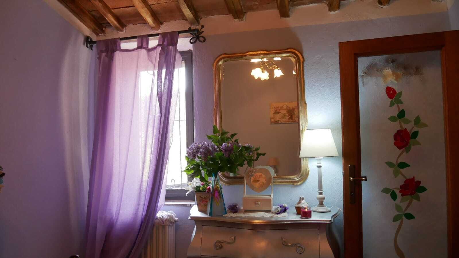 A room with a vanity, a mirror, a lamp, and a door with a floral design.