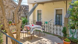 Eine Terrasse im Freien mit Tisch und Stühlen, Blumentöpfen und einer Steinmauer.