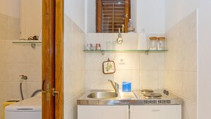 Eine kompakte Küche mit integriertem Kühlschrank, Spüle und einem Fenster über der Arbeitsfläche.