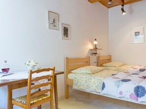 Un dormitorio con una cama de madera, una mesita de noche con una lámpara y dos cuadros en la pared.