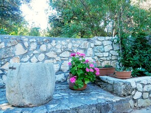 Stonework features a large planter and two smaller pots amidst lush greenery.