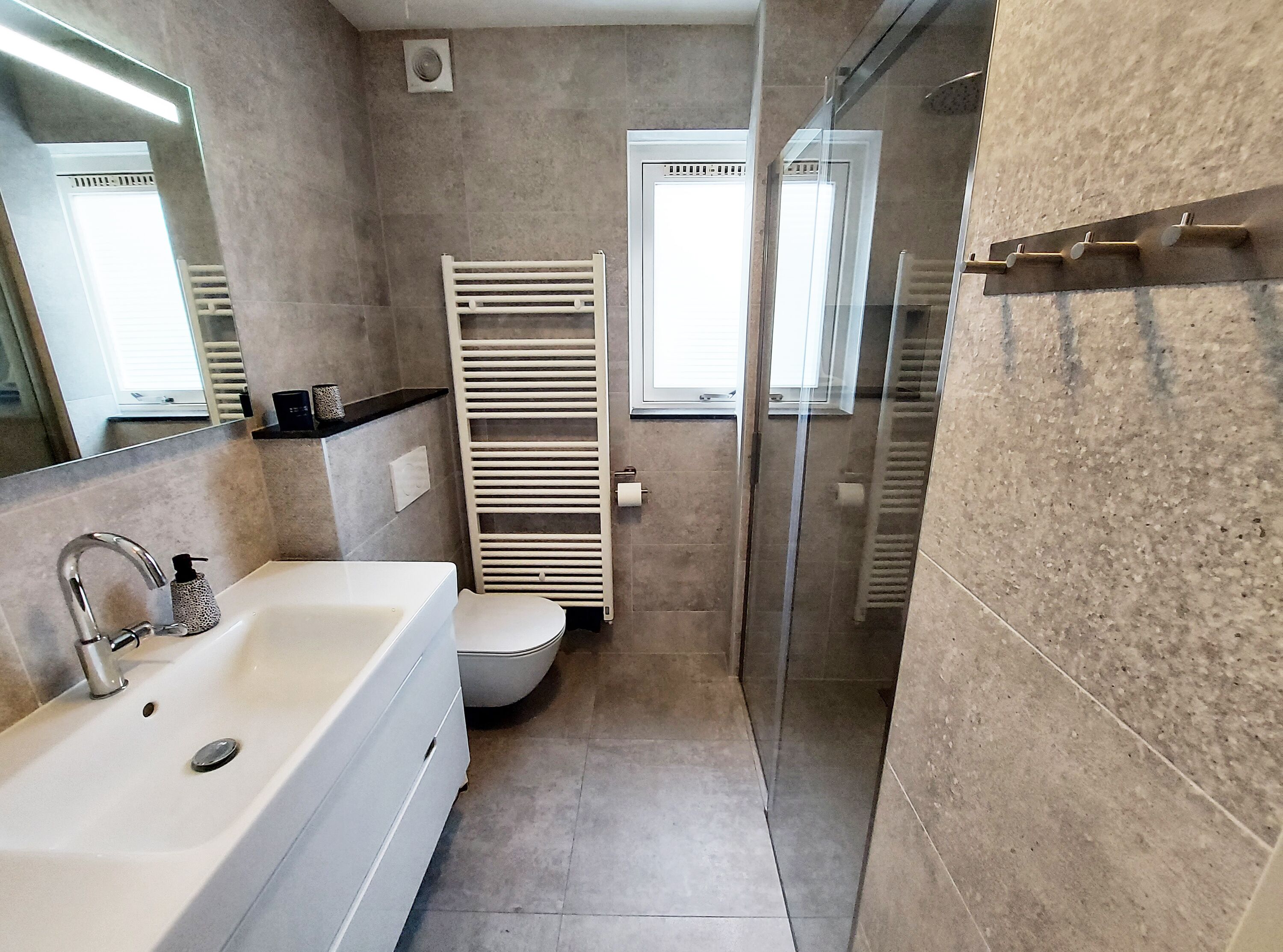 Ein modernes Badezimmer mit Waschbecken, Spiegel und Dusche.
